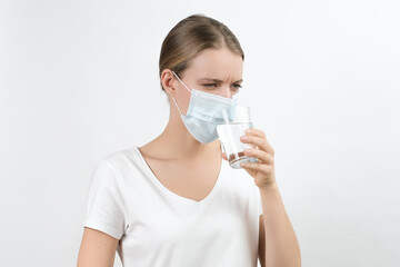 white woman in medical protection mask trying to drink water and is angry. 