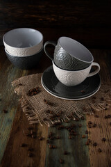 Ceramic tableware and scattered coffee beans on a wooden table