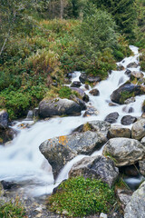 Water flowing between the stones of this mountain waterfall on an autumn day. The waterfall conveys wellbeing, serenity and tranquility.