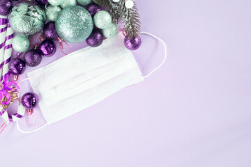 Christmas decorations and a medical mask on a purple background.