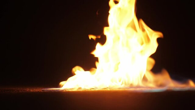 Mans hand throw a match in a gasoline puddle and makes in flame with blue fire. Circle of fire burn in the dark