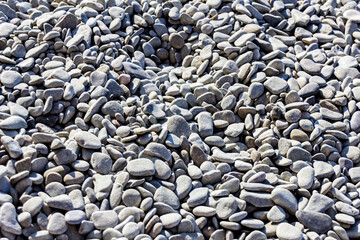 Grey sea pebbles on sunny day