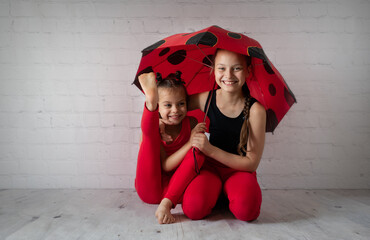 Sisters in red clothes sitting under umbrella