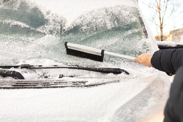 A man cleans snow from his car in winter.