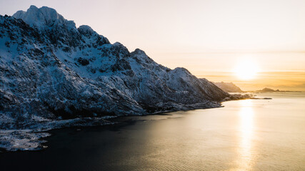 Naklejka premium Breathtaking bird's eye view of majestic fjord mountains covered with snow in winter. Aerial view of scenery rock peaks, picturesque beautiful nature landscape. Lofoten Island surrounds by Nordic sea