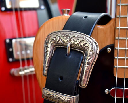 Electric guitars and leather strap with silver buckle close-up.