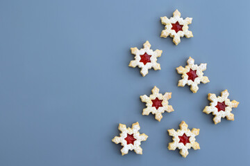 Homemade linzer cookies in a shape of snowflakes filled with strawberry jam, top view, copy space