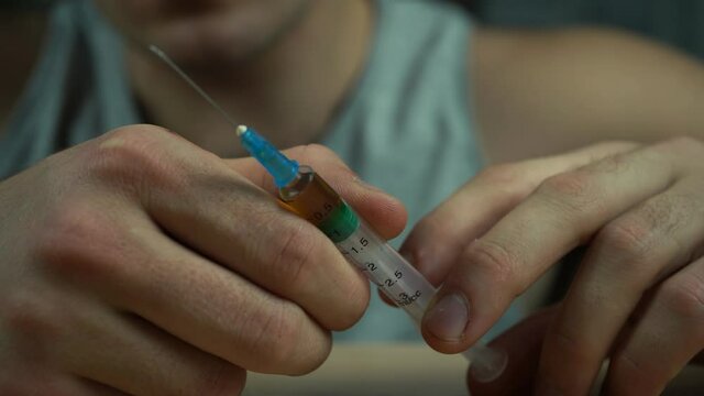 a man holding a syringe with a drug in his hands. addiction concept
