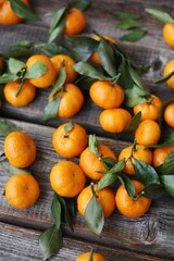 Fototapeta na wymiar Juicy tangerines with green leaves on a wooden table 