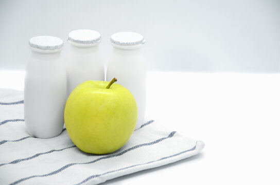 Natural liquid yogurt with prebiotics in small plastic bottle and green apple on white background. Healthy, balanced diet food, healthy breakfast. Space for text.