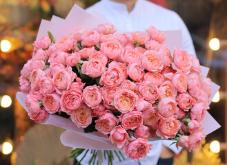 Young man with a gift bouquet of pink spray roses, mono bouquet of roses. Young man holding fresh...