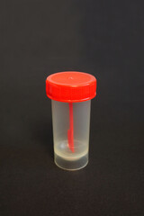 closed plastic red container for collecting feces on a black background side view . the collection of tests