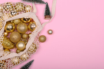 Eco-friendly bag with golden Christmas balls and christmas tree on a pink background