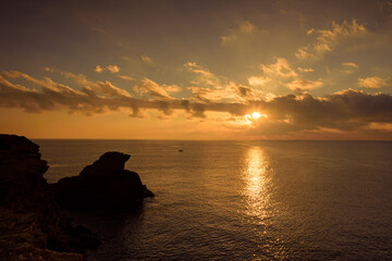 Naklejka na ściany i meble Beautiful cloudy sunrise from a cliff in Cabo de Palos with the sun reflected in the sea water, Murcia, Spain