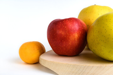 Apples and tangerine on a cutting board