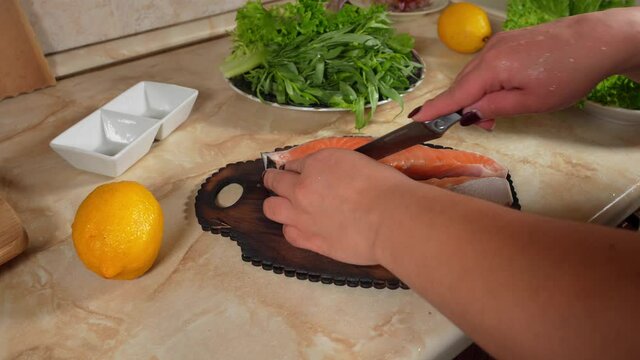 Woman's hand cuts a piece salmon fish