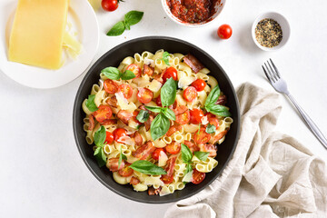 Tomato and bacon pasta with parmesan cheese and basil leaves
