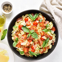 Tomato and bacon pasta with parmesan cheese and basil leaves