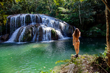 Beautiful woman in a bikini close to a waterfall