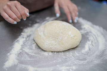 Close up of woman's hands kneading dough in bakery kitchen