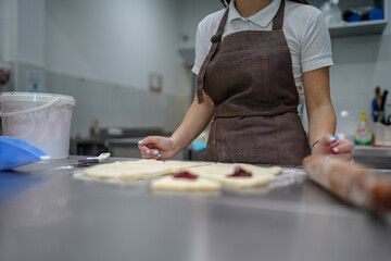 Young woman making croissants in bakery kitchen