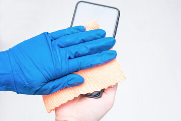 Person wipes phone, hand in a blue glove with a cleaning cloth, a  close-up