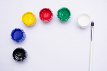 Cans of different colors gouache paints and artist brush, white background, copy space