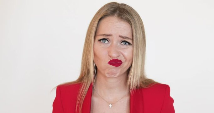 Stock video of disappointed blonde woman with makeup in red jacket showing sympathy and displeasure to the camera.