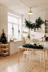 Interior of a light kitchen decorated with Christmas decorations and fir plants in natural materials and colors in a cozy home