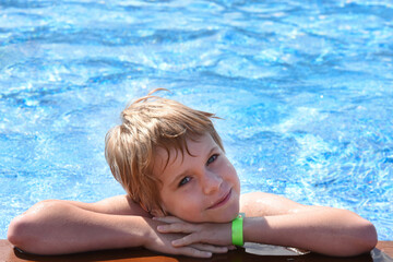 Fototapeta na wymiar Cute baby smiles. The girl in the pool looks at the camera and smiles. Space for text