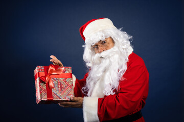 Retrato de papa noel con regalo en las manos en fondo azul