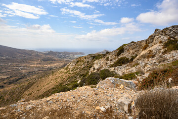 A view of rocky coast of Ios Island. Chora town and port in the background. Cyclades, Greece