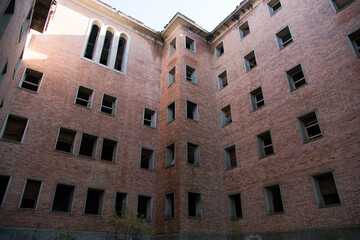 Esquina de un edificio abandonado de ladrillos rojos con ventanas rotas