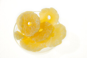 Yellow candied pineapple rings in a glass vase on a white background, top view