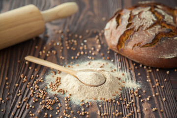Spoon with buckwheat flour on a wooden background