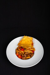 Pieces of meat with pasta on plate and black background