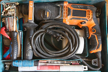  A man using an electric hand drill for work with a timber board, holes and door hinge, sawdust all around