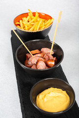 Sausages with french fries on black plate and white background
