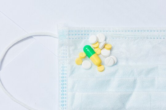 Medical mask protection against pollution and colorful pills with medicines, top view, cropped image, closeup,  copy space