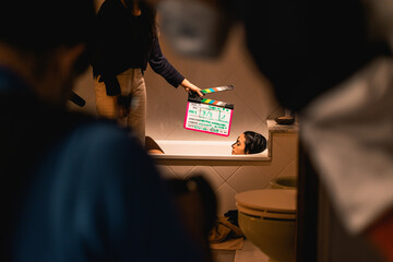 A filming clapper board in a lavatory scene with the actress in the bathtub