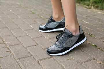 female feet wearing black sneakers outdoors