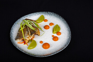 Tuna steak covered with broccoli and decorations on white plate and black background