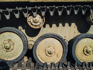 Steel black track and wheels from a Soviet military tank T-70. Tread texture, metal background.