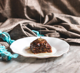 Perfect sweet turkish baklava with pistachio on marble background and wooden honey dipper
