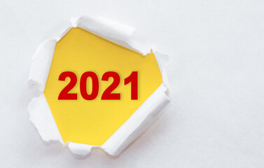 Top view of white torn paper and text 2021 on yellow background.