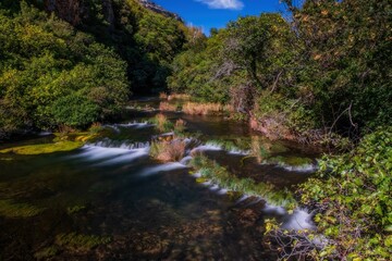 Fototapeta na wymiar The turquoise Krka waterfalls in Croatia captured from the wooden bridge. Long exposure picture. September 2020