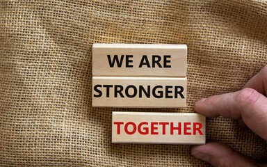 Wooden blocks with words 'we are stronger together'. Beautiful canvas background, male hand. Copy space. Business concept.