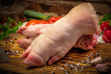 Raw fresh pig feet, trotters on wooden background with vegetables and spices. 
