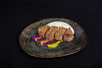 Tuna steak on black plate with decoration