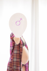 A pregnant woman is holding a pink balloon  - Young pregnant girl is behind and taking in the hand the balloon during maternity time